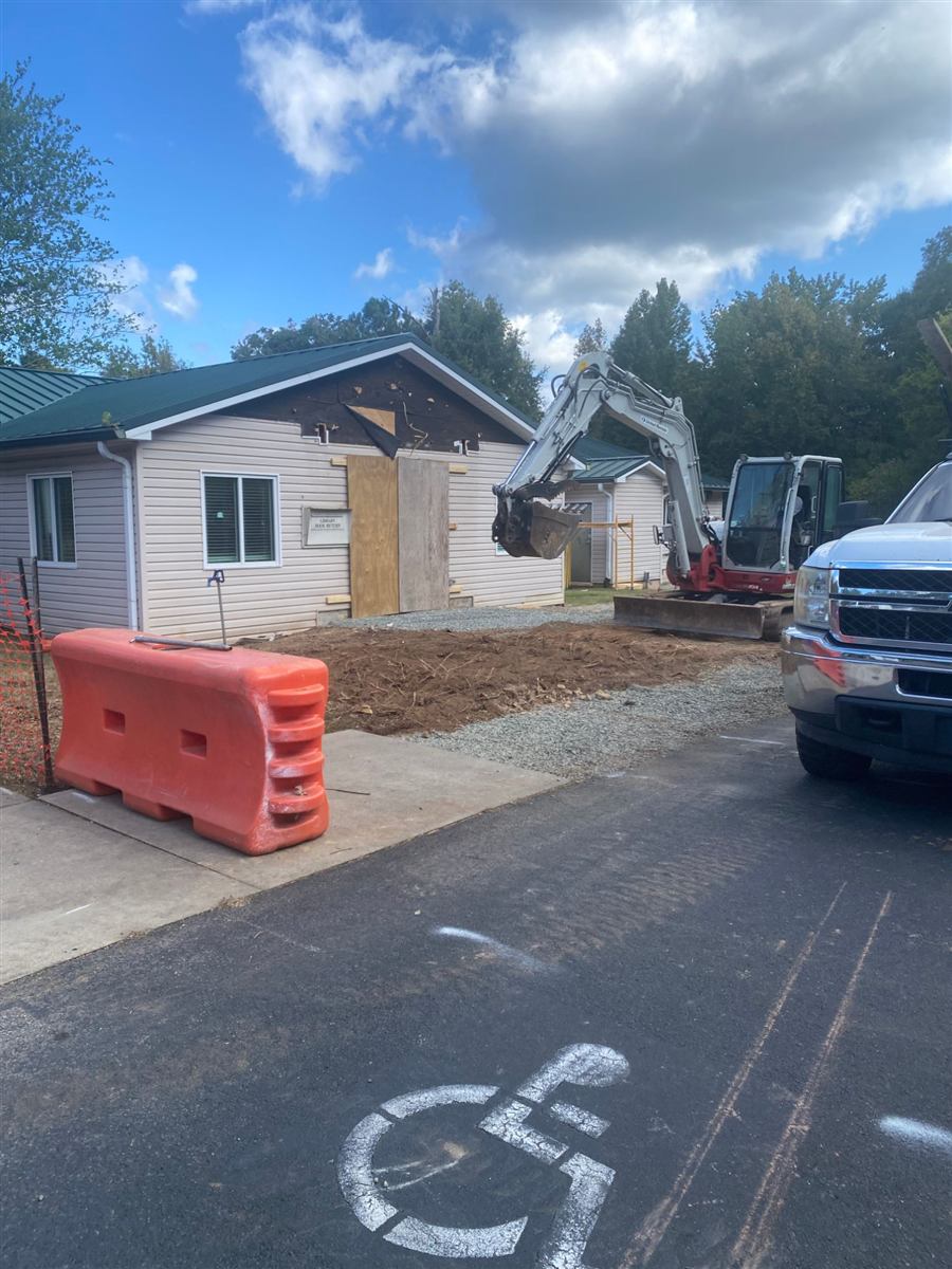 The library’s front wall opened up and boarded, with an excavator working in front